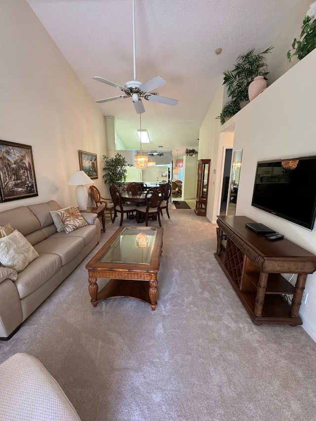 carpeted living room featuring a textured ceiling, high vaulted ceiling, and ceiling fan