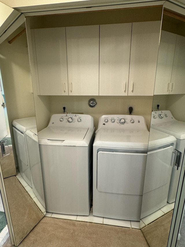 laundry area with washer and clothes dryer, cabinet space, and light tile patterned flooring
