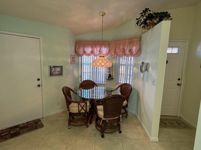 dining area featuring tile patterned floors, a textured ceiling, baseboards, and lofted ceiling