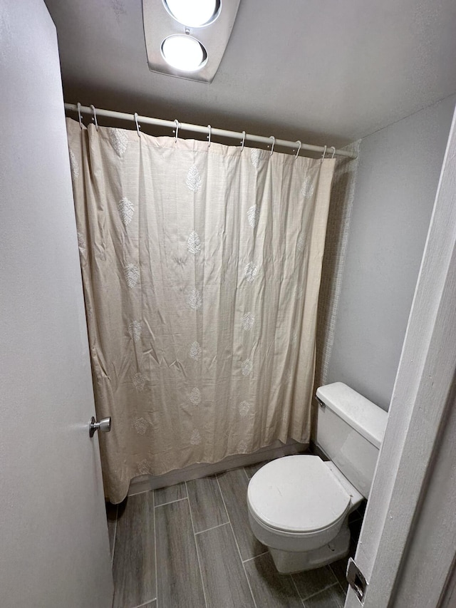 full bath featuring toilet and shower / tub combo with curtain