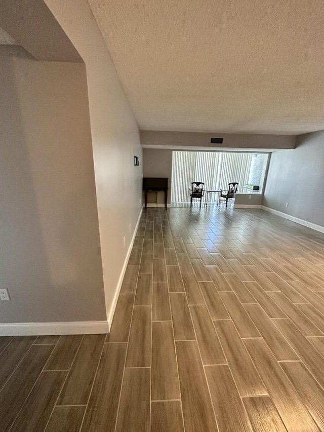 hall with visible vents, wood finished floors, and baseboards