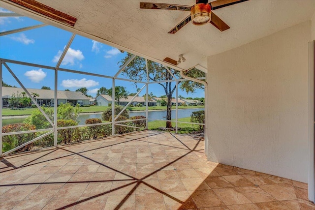 view of patio / terrace featuring glass enclosure, a residential view, a water view, and a ceiling fan