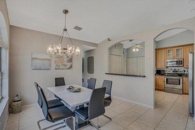 dining space featuring visible vents, arched walkways, lofted ceiling, ceiling fan with notable chandelier, and light tile patterned floors