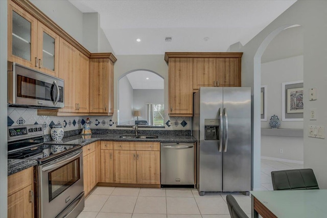 kitchen with arched walkways, a sink, light tile patterned flooring, and appliances with stainless steel finishes