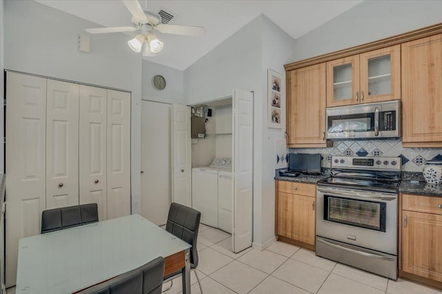 kitchen with light tile patterned flooring, stainless steel appliances, vaulted ceiling, backsplash, and washer and clothes dryer