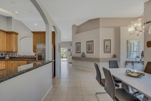 dining space featuring an inviting chandelier, light tile patterned floors, arched walkways, and a healthy amount of sunlight
