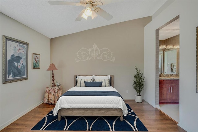 bedroom featuring a ceiling fan, baseboards, ensuite bath, and wood finished floors
