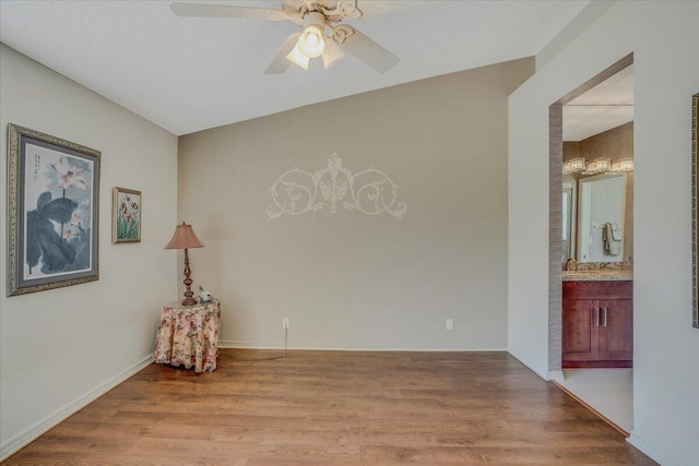 empty room with a ceiling fan, a sink, baseboards, and wood finished floors