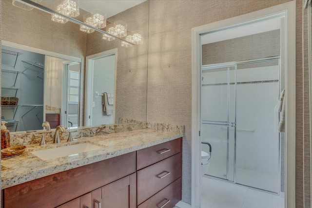 bathroom featuring toilet, a stall shower, a chandelier, and vanity