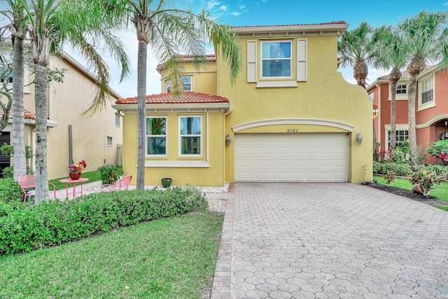 mediterranean / spanish-style house featuring stucco siding, decorative driveway, a tiled roof, and an attached garage