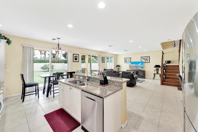 kitchen featuring light stone countertops, a kitchen island with sink, light tile patterned floors, dishwasher, and a sink