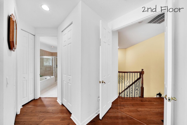 hall featuring an upstairs landing, wood finished floors, visible vents, and recessed lighting