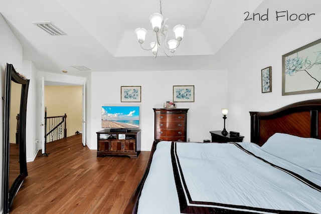 bedroom with an inviting chandelier, wood finished floors, and visible vents