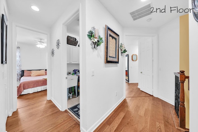 corridor featuring light wood finished floors, recessed lighting, visible vents, and baseboards