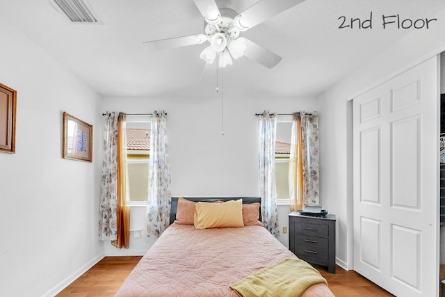 bedroom with visible vents, a ceiling fan, light wood-style flooring, and baseboards