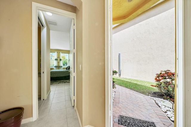 hall featuring baseboards, visible vents, and light tile patterned flooring