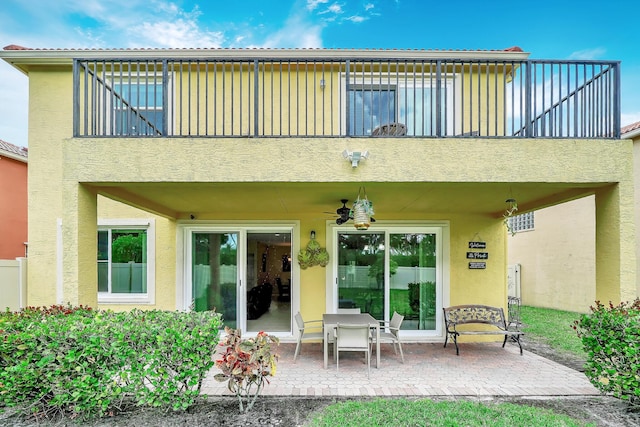 back of house featuring a balcony, a ceiling fan, stucco siding, and a patio area