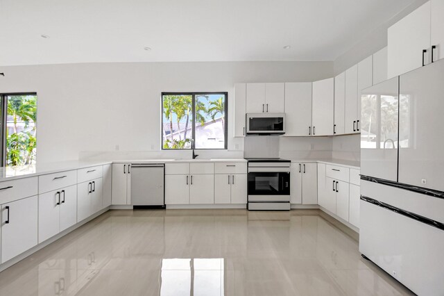 kitchen with a wealth of natural light, white appliances, light countertops, and a sink