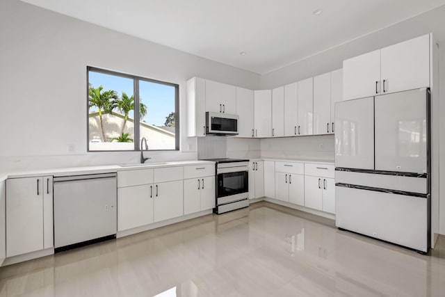 kitchen featuring white appliances, light countertops, a sink, and white cabinetry