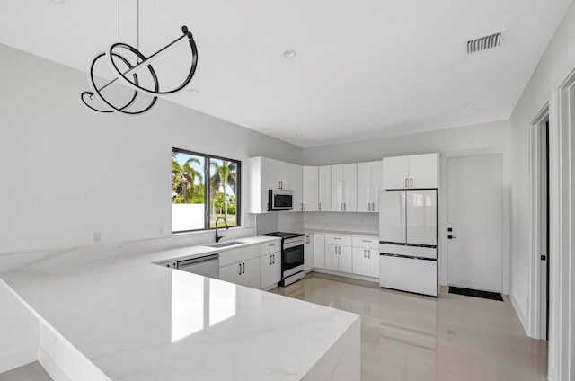 kitchen featuring white cabinets, a sink, light countertops, appliances with stainless steel finishes, and a peninsula