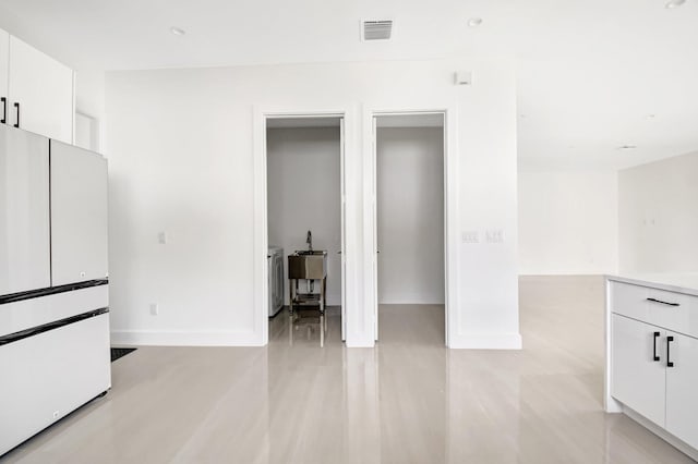 unfurnished bedroom featuring a sink, freestanding refrigerator, baseboards, and visible vents