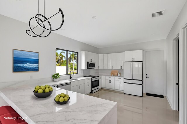 3920 Espan Ct, Palm Springs, FL 33461 - kitchen with stainless steel appliances, a sink, a peninsula, white cabinetry, and light tile patterned floors