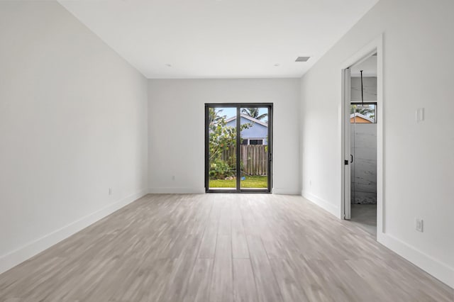 spare room featuring visible vents, baseboards, and wood finished floors