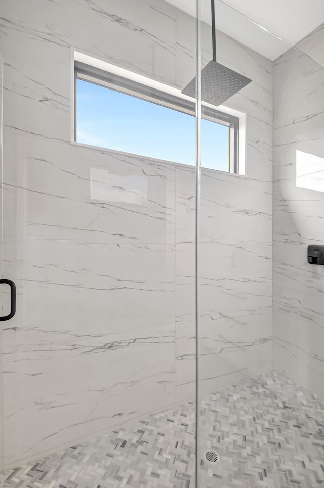 full bath with a marble finish shower and a healthy amount of sunlight