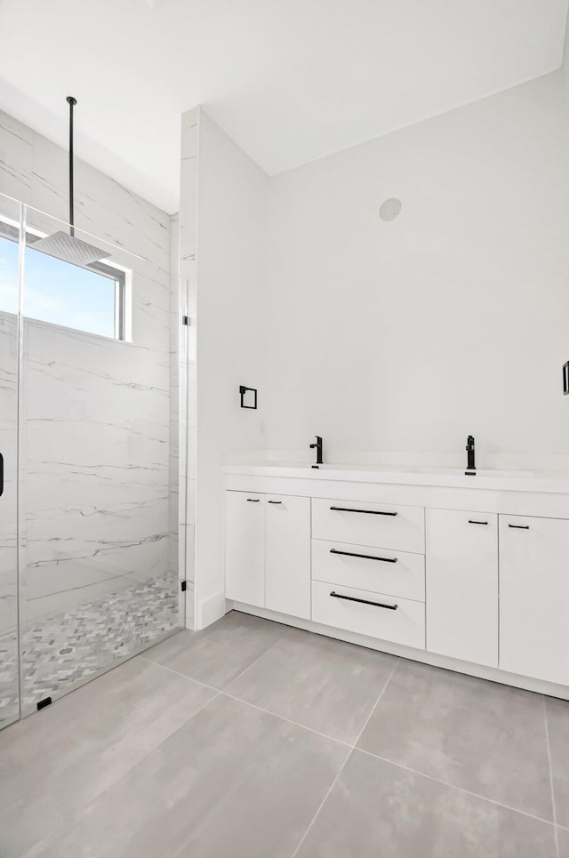 bathroom with double vanity, a marble finish shower, and tile patterned flooring