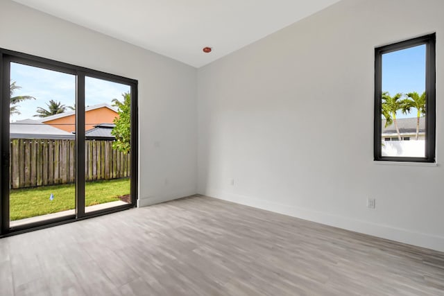 spare room featuring a healthy amount of sunlight, wood finished floors, and baseboards
