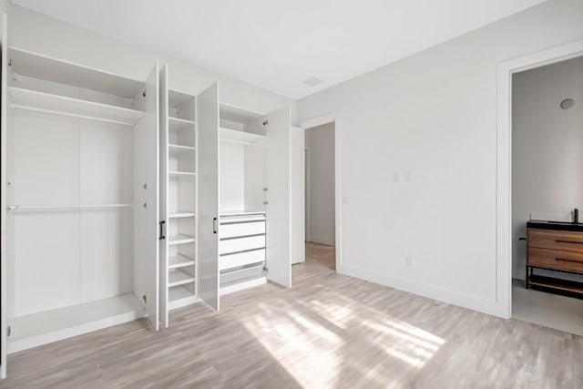 unfurnished bedroom featuring a closet, baseboards, and wood finished floors