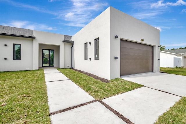 modern home with concrete driveway, a front yard, and stucco siding