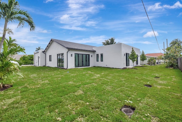 rear view of property with stucco siding and a lawn