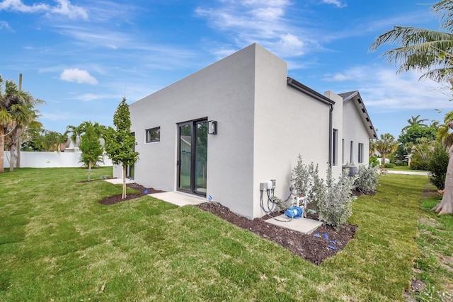 back of property featuring a yard, stucco siding, and fence