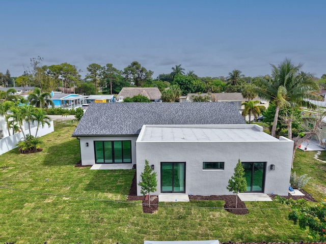 back of property with a yard, stucco siding, and fence