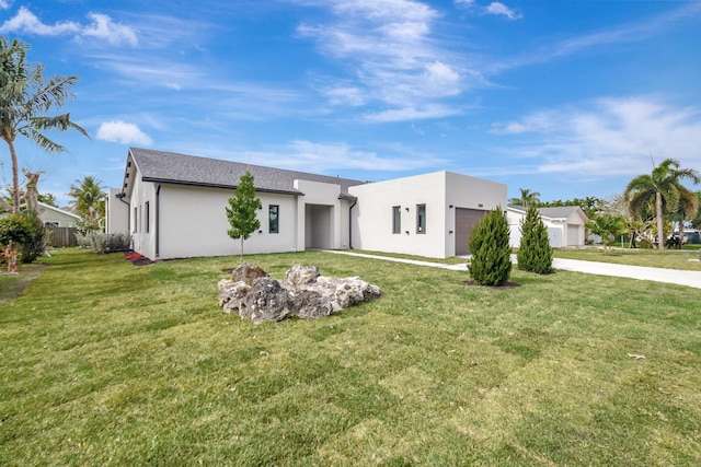 view of front of house featuring driveway, stucco siding, a front lawn, and a garage