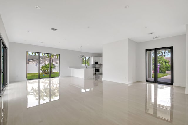 unfurnished living room featuring plenty of natural light, visible vents, and baseboards