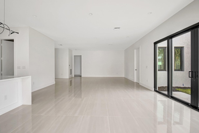 empty room featuring light tile patterned floors, visible vents, and baseboards