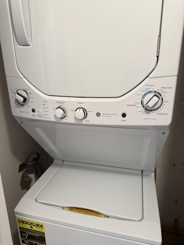 clothes washing area featuring stacked washer and dryer and laundry area