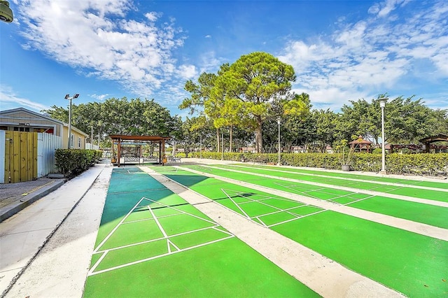 view of property's community with shuffleboard and a pergola