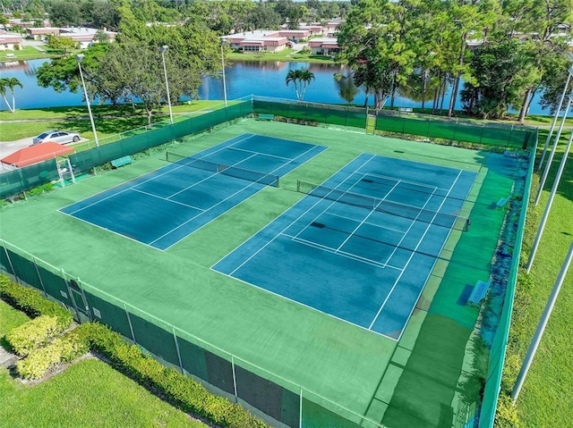 view of sport court with a water view and fence