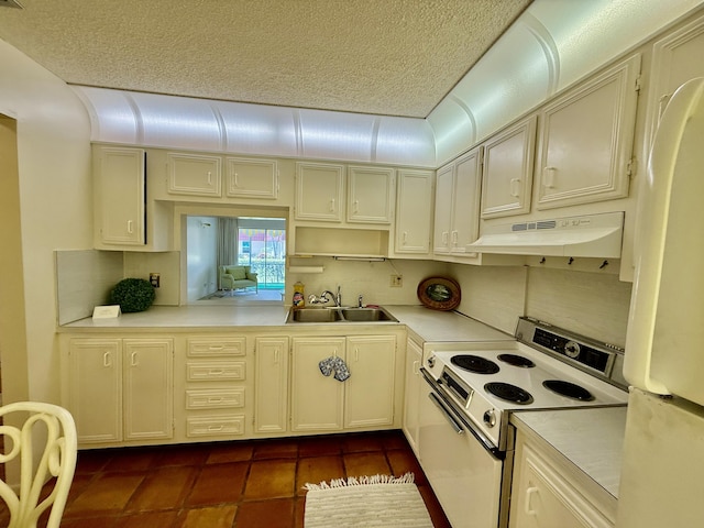 kitchen featuring light countertops, white appliances, under cabinet range hood, dark tile patterned flooring, and a sink