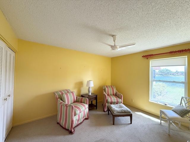living area with carpet flooring, a textured ceiling, baseboards, and ceiling fan