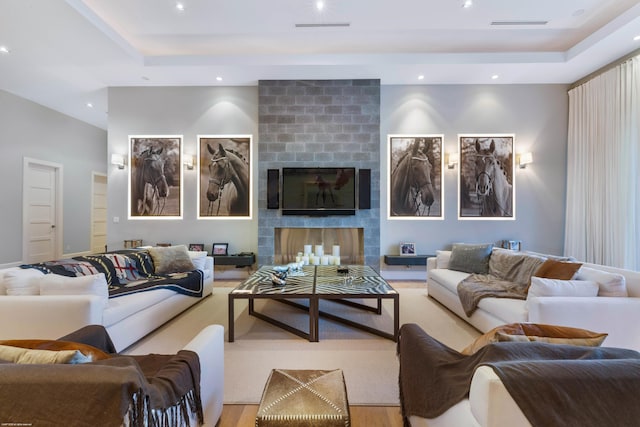 living room with recessed lighting, a large fireplace, visible vents, and a raised ceiling