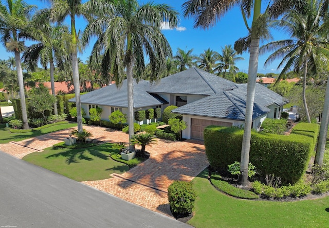 view of front facade with an attached garage, a tiled roof, decorative driveway, and stucco siding