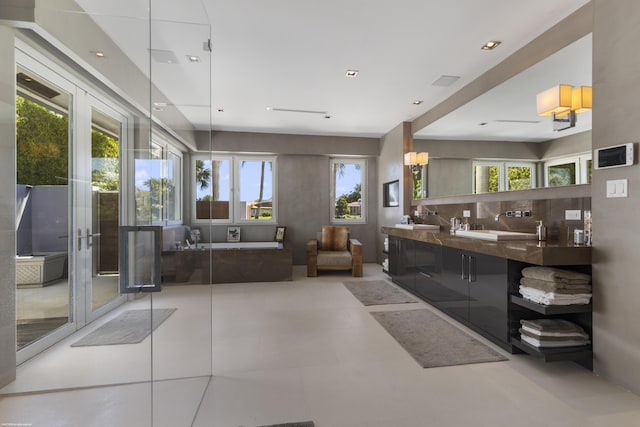 interior space with a bath, a healthy amount of sunlight, and double vanity