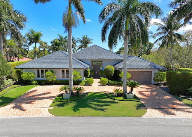 ranch-style home featuring stucco siding, a tile roof, decorative driveway, and a garage