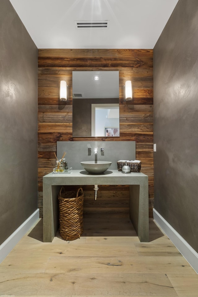bathroom featuring visible vents, vanity, wood finished floors, and wooden walls