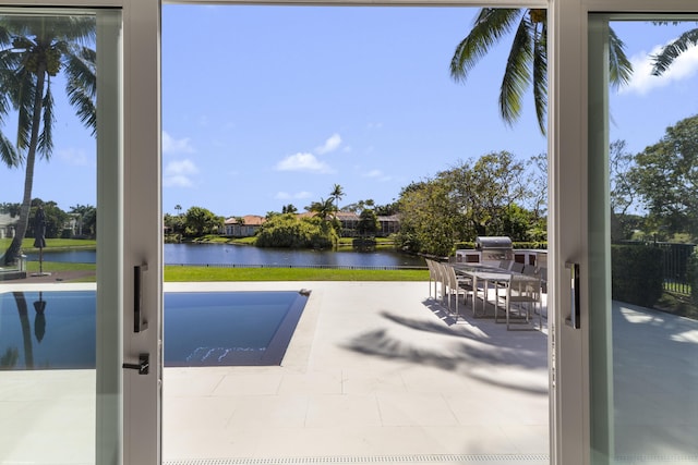 view of swimming pool featuring a patio, area for grilling, and a water view