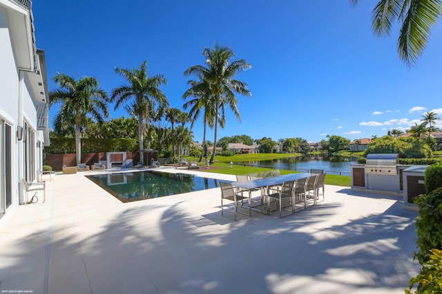 outdoor pool with a water view, grilling area, outdoor dining area, a patio, and exterior kitchen